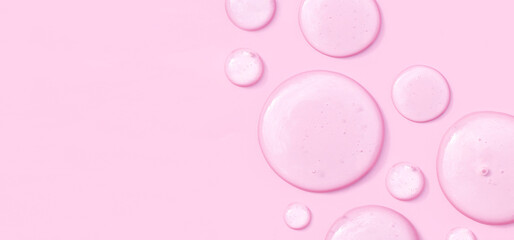 round drops of transparent gel serum on pink background