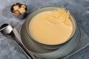 Cheese soup with croutons on a gray background.