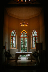 Valmiera, Latvia - September 9, 2023 - Dimly lit church altar with a large wooden cross, floral...