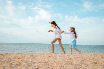 Fototapeta premium Sister's children relax, play and have fun on the sandy seashore