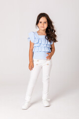 Happy little girl in white summer pants and blue blouse on white background. Copy space. advertising of goods for children