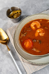 Tom yum soup with seafood, capers added nearby.
