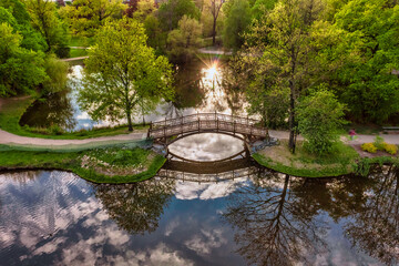 Wooden Bridge over Lake in Park / Aerial Shot, sunset rays in water reflection