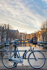 Bicycle and boats parked along the building lined canals in Amsterdam. Photo taken during the daytime in Amsterdam Holland