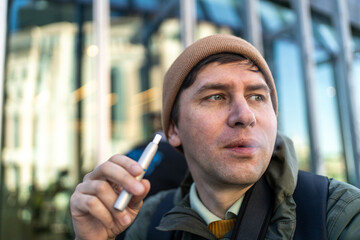 Man Smoking E-cigarette or Tobacco Heating System Outdoors. 