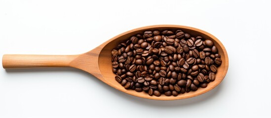 Fototapeta premium Top view image of coffee beans in a wooden scoop against a white backdrop with copy space image