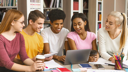 Students studying in library. Group of young people working with laptop and communicating in library together