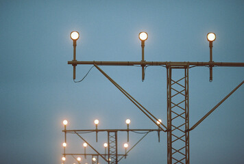 Close-up of illuminated approach lights on a metal structure at dusk, captured on film with visible fog