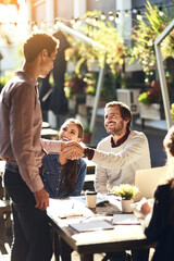 Business people, group and shaking hands in meeting at cafe for welcome, b2b networking or collaboration outdoor. Team, employees and handshake for onboarding, partnership deal or happy for agreement