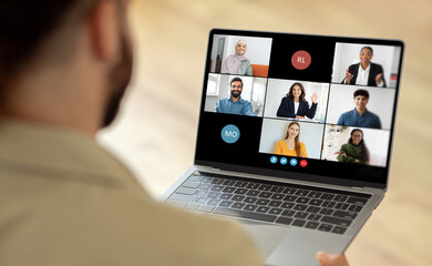 Man using a laptop while a group of people are visible on the screen. The person is engaged in virtual communication or collaboration with the individuals displayed on the laptop screen.