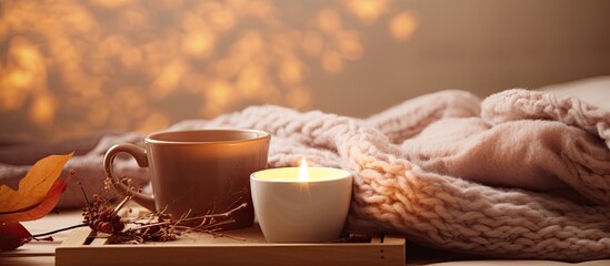 Autumn weekend concept for fall home decoration featuring a cup of coffee on a rustic tray a candle a cozy woolen sweater and decorated with LED lights in a living room setting with copy space image