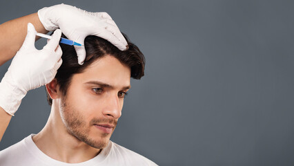 Man with hair loss problem receiving injection in head, grey background, empty space