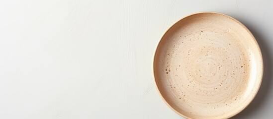 Neutral beige pottery plate on a white studio backdrop in a high angle view for food styling in advertising with copy space image