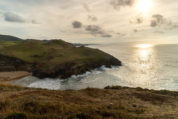 Sunset in the atlantic sea, in a yellow and brown scene with the beach and cliffs