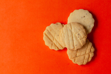 Stacked carrom seed cookies or salted ajwain cookies on an orange background. Top-down view. Food Flat lay.