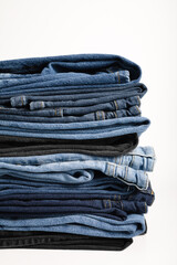 A beautiful stack of folded denim jeans in different shades of blue and black. Denim background