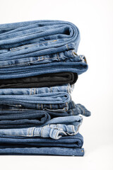 A stack of folded jeans in various shades of blue and black on a white background.