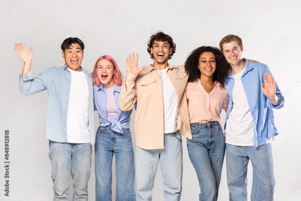 Wall mural A group of five young adults, representing diverse ethnicities and genders, stand together against a white background. They are all smiling and appear to be happy and friendly.