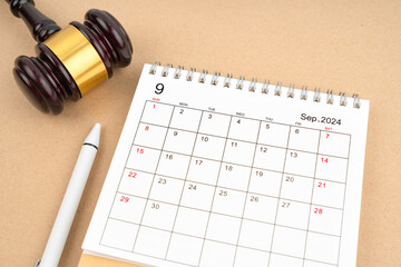 Desk calendar for September 2024 and judge's gavel on brown background.