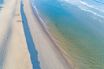 group of surfers on the shore of a beach at sunrise as seen from a drone