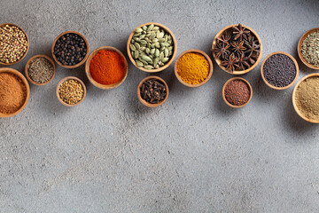 A variety of spices in wooden bowls on a gray background with copyspace top view