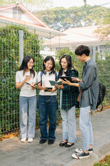 Young college students is reading a book while relaxing sitting on grass in a campus park with her friends. Education concept in morning