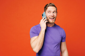 Young smiling happy man he wearing purple t-shirt casual clothes talk speak on mobile cell phone...