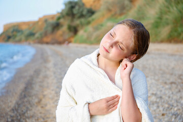 The child got water in his ear while swimming in the sea. The girl cleans her ear from water.