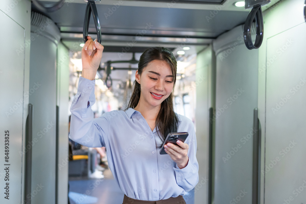 Wall mural asian woman traveler using mobile phone device while riding on the train.