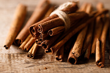 Cinnamon sticks dried tree bark spice on rustic wooden table background. Selective focus.