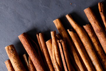 Cinnamon sticks dried tree bark spice on black stone table background. Selective focus.