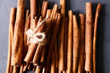 Cinnamon sticks dried tree bark spice on black stone table background. Selective focus.