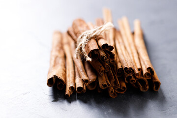 Cinnamon sticks dried tree bark spice on black stone table background. Selective focus.