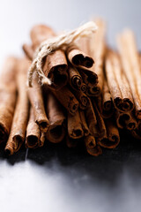 Cinnamon sticks dried tree bark spice on black stone table background. Selective focus.