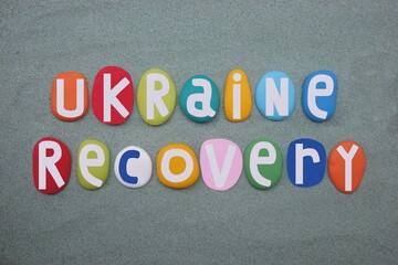 Support Ukraine, Ukraine Recovery, motivational slogan composed with hand painted multi colored stone letters over green sand