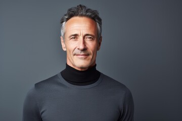 Fototapeta premium Portrait of a satisfied man in his 50s wearing a classic turtleneck sweater isolated on minimalist or empty room background