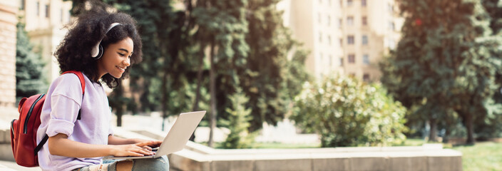 E-Learning. African American Girl Student Using Laptop Learning Sitting Near University Building Outdoor. College Education And Modern Study, Educational Gadgets And Computers Concept, Copy Space