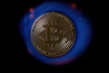 A bitcoin coin in the tongues of a hot flame. Real photo