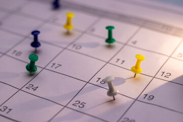 Closeup of Colorful Push pin in calendar. Calendar page pinned in calender on date, business meeting schedule or travel planning concept. and reminder concept. Calendar appointment