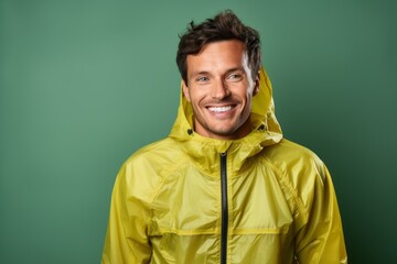 Portrait of a smiling man in his 30s wearing a lightweight packable anorak isolated on solid color backdrop