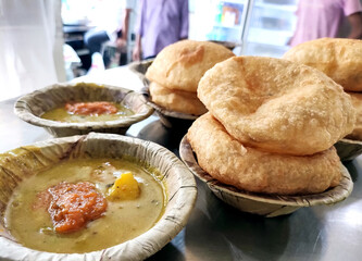 Bedmi puri and potato curry kept in a leaf container (Dona) on the table