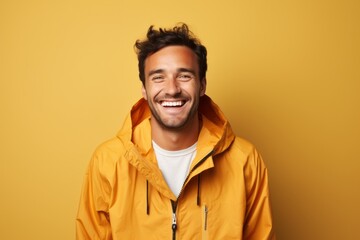 Fototapeta premium Portrait of a smiling man in his 30s wearing a lightweight packable anorak while standing against solid color backdrop