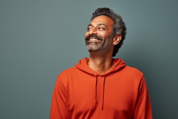 Obraz premium Portrait of a blissful indian man in his 40s dressed in a comfy fleece pullover in solid color backdrop