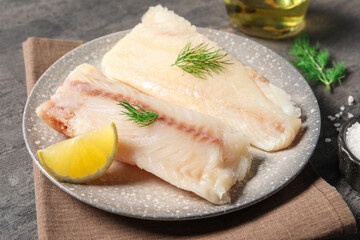 Pieces of raw cod fish, dill and lemon on grey table, closeup