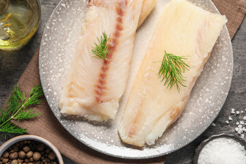 Pieces of raw cod fish and spices on table, top view