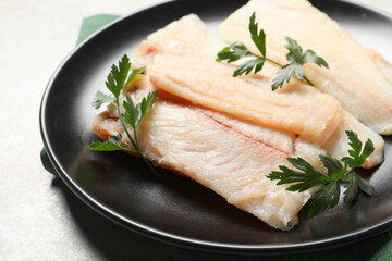 Plate with raw cod fish and parsley on light table, closeup