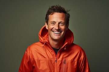 Obraz premium Portrait of a smiling man in his 40s wearing a lightweight packable anorak while standing against solid color backdrop