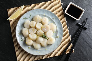 Raw scallops with lemon, rosemary and soy sauce on dark textured table, flat lay