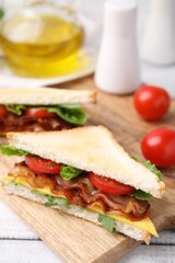 Delicious sandwich with fried bacon on wooden rustic table, closeup