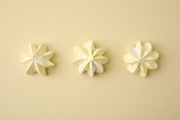 Delicious meringue cookies on beige background, flat lay